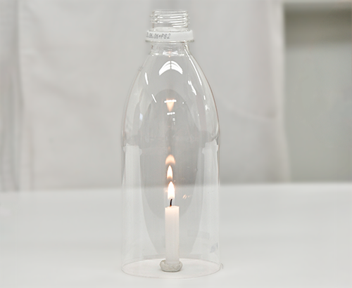 底は閉じ、蓋が開いてるペットボトルを火のついたろうそくにかぶせている写真