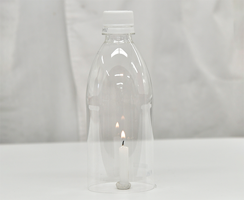 底をくりぬいたペットボトルに蓋をして火がついたろうそくにかぶせている写真