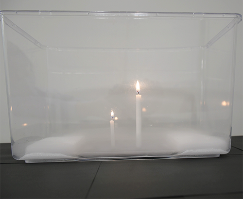 水槽の中にドライアイス、火のついた大小のろうそくが入っている写真