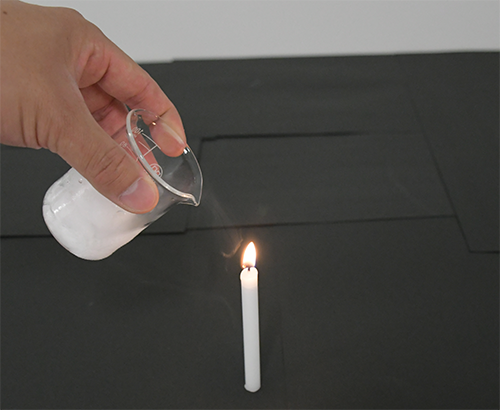 ろうそくの火にビーカーに入ったドライアイスを近づける写真